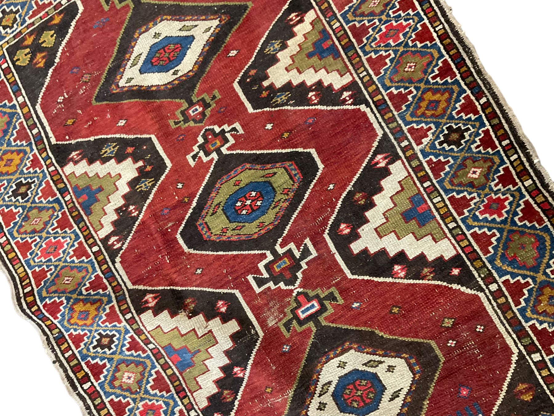 Anatolian Turkish red ground rug, decorated with three central lozenges, the multi-colour guarded border with repeating geometric shapes