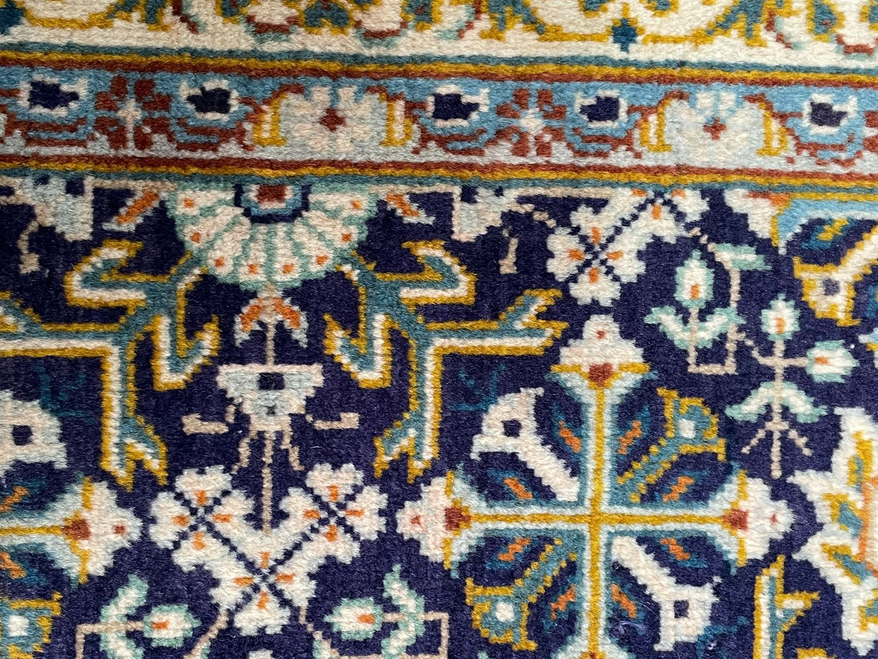 Persian indigo and pale gold ground rug, overall busy geometric design, the field decorated with hooked Hac and palmette medallions surrounded by densely patterned zig-zags and stylised foliate motifs, the border decorated with smaller Hac motifs, within multiple guard stripes 