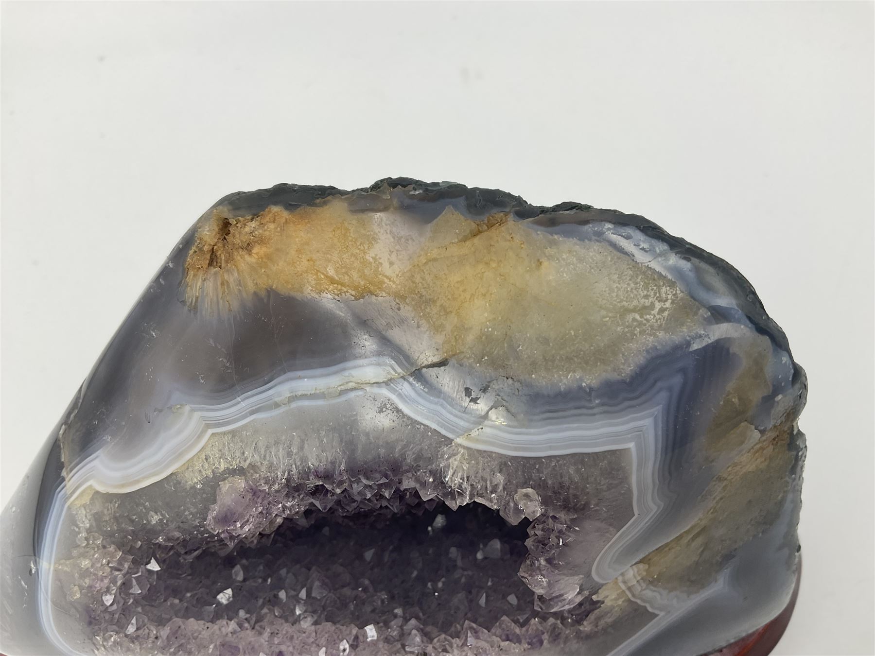 Amethyst crystal geode cluster, with well-defined crystals of various sizes, upon a carved wooden stand, H12cm, L20cm