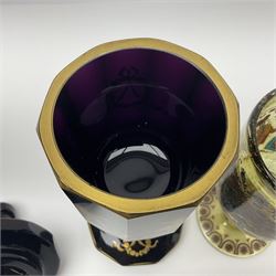 19th Century Bohemian amethyst glass lidded goblet, the bowl of faceted form, gilded with three children in period dress playing games, upon a knopped stem and conforming faceted foot, together with an art nouveau green glass goblet, with gilded rim, upon clear trumpet stem, and a hand blown wine glass, transfer printed with birds and three figures in period dress, tallest H29cm