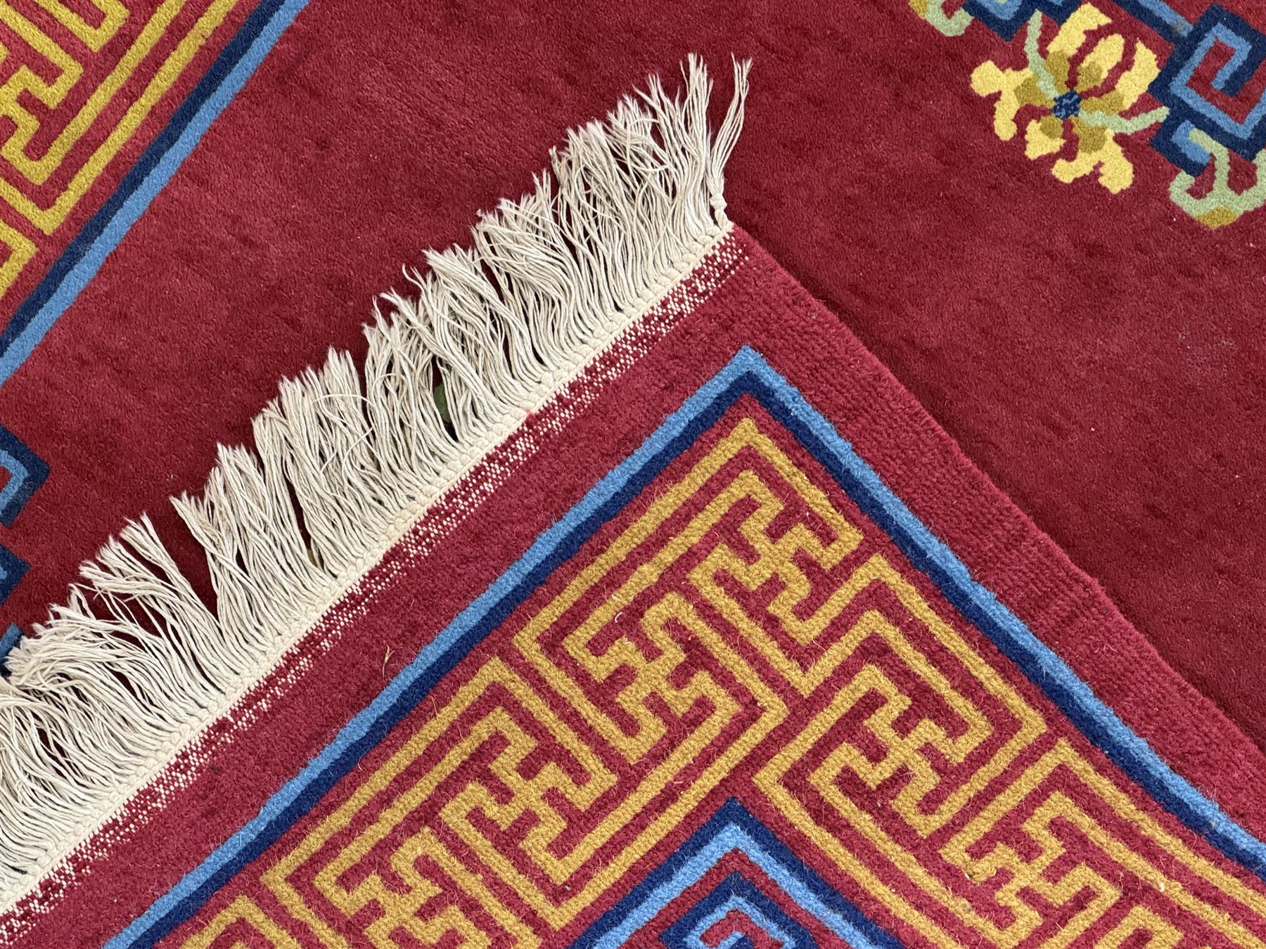 Tibetan-design handwoven rug, deep red field with three central medallions in yellow and blue, traditional yellow key border, white fringes on both ends