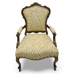 Victorian mahogany framed upholstered armchair, shaped and scroll carved cresting rail above a padded upholstered back with applied braid trim, swept open arms with carved terminals and upholstered arm pads, over a serpentine fronted deep stuffed seat, raised on cabriole forelegs terminating in carved claw feet