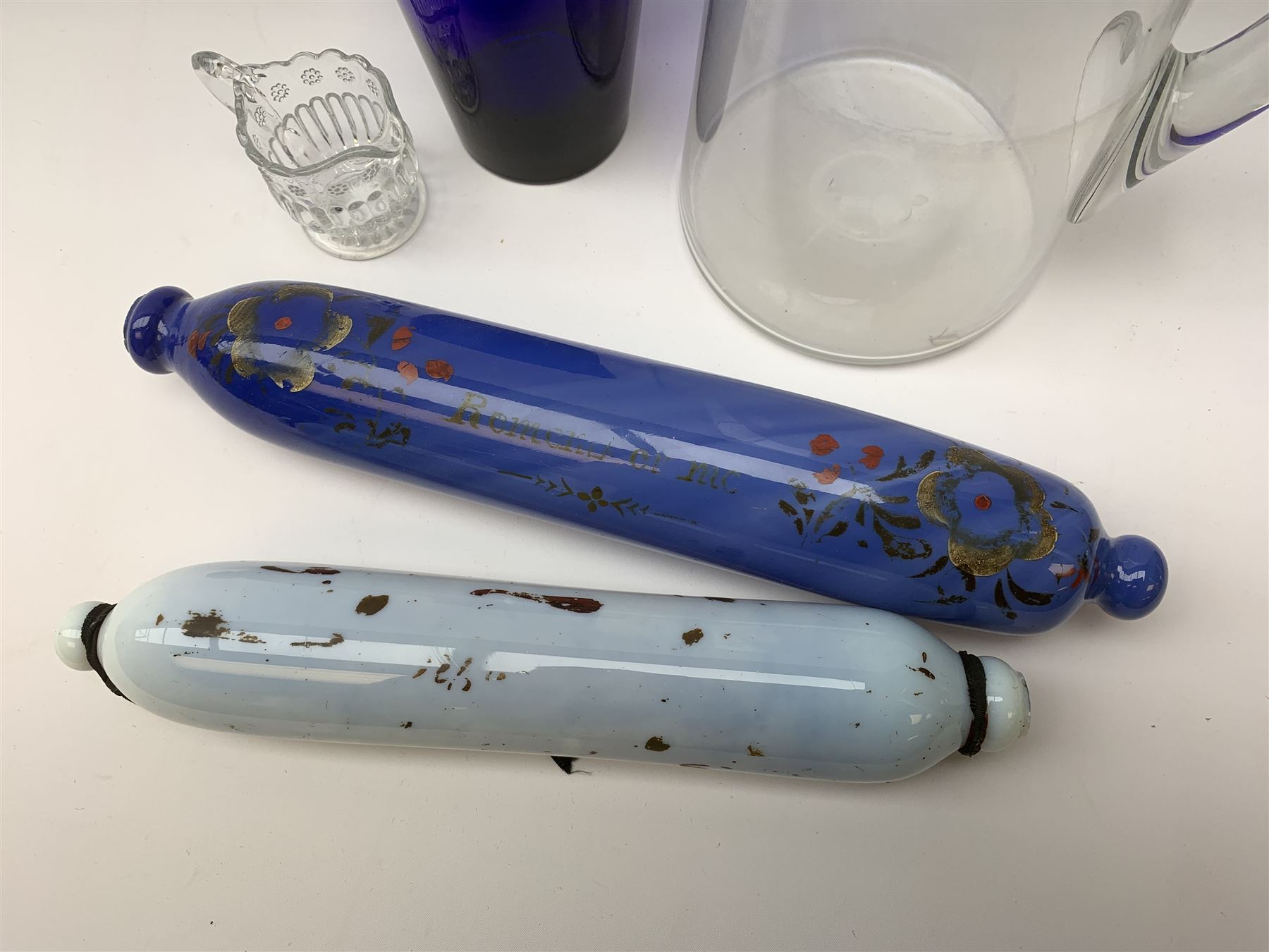Two Victorian glass rolling pins, the larger blue example inscribed 'Remember Me' between floral sprays, largest L33.5cm, together with a late Victorian clear glass jug, H24cm, Bristol Blue type tumbler, and small moulded cream jug. 