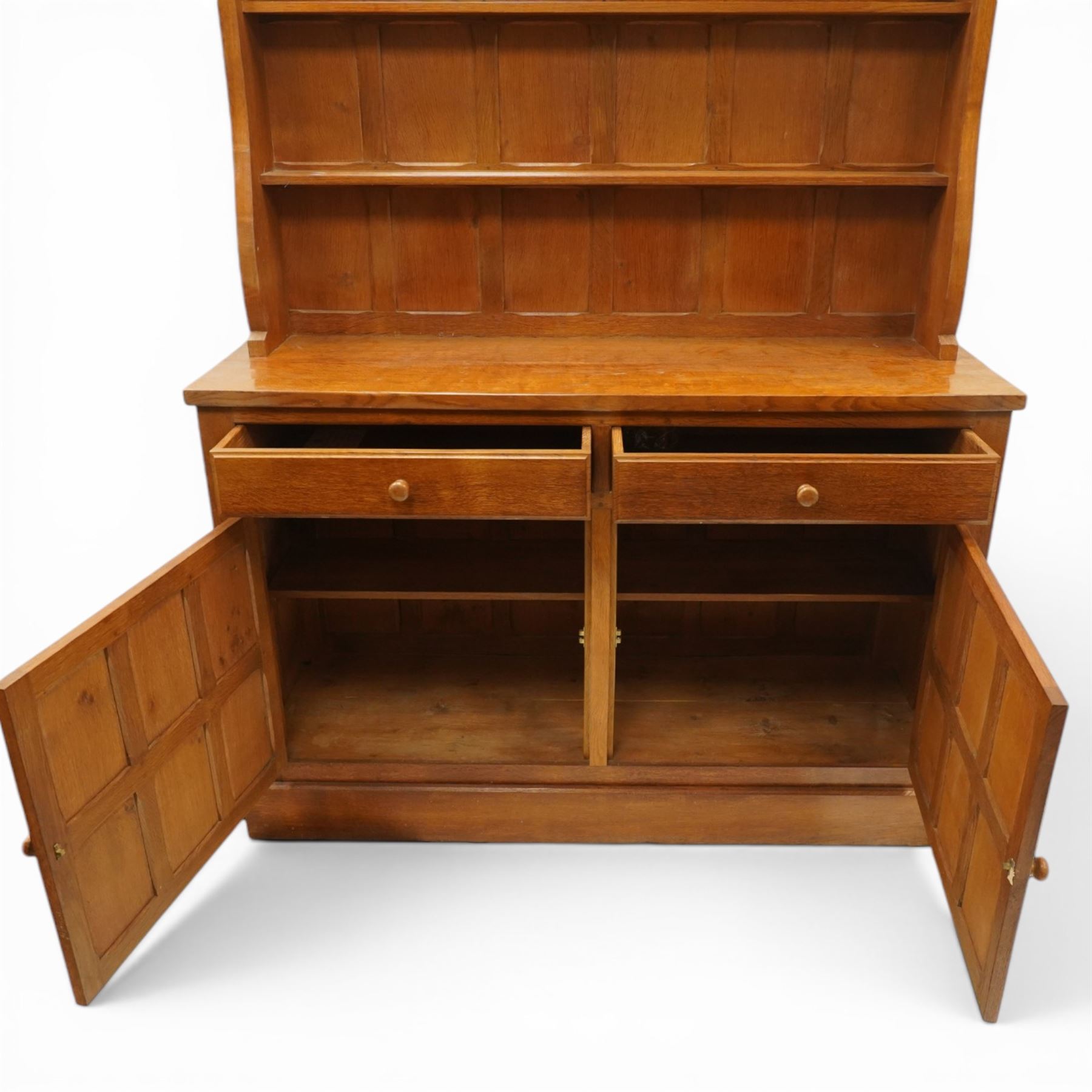 Cat and Mouseman - adzed oak dresser and plate rack, plate rack with two delf rack, panelled back and shaped uprights, above a base with two short drawers and turned wooden handles, panelled cupboard doors and sides, raised on a plinth base, with carved Cat and Mouseman signature, by Lyndon Hammell of Harmby