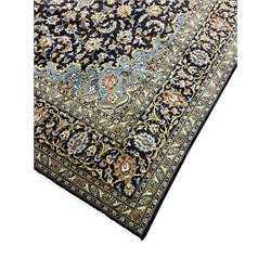 Persian Kashan indigo ground carpet, floral pattern light blue ground central medallion and spandrels, the fielding decorated with interlacing leafy branches and palmettes, the repeating floral pattern border enclosed within guard stripes