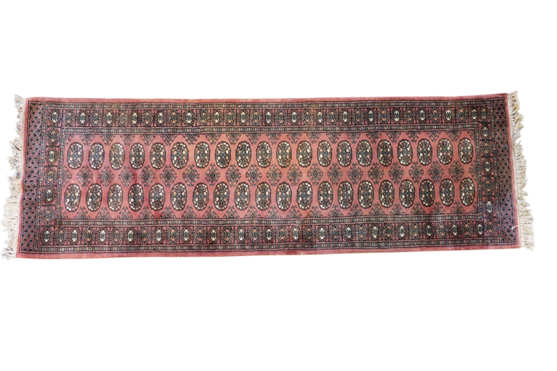 Afghan pale red ground runner, the field decorated with two rows of Gul motifs, within repeating patterned border