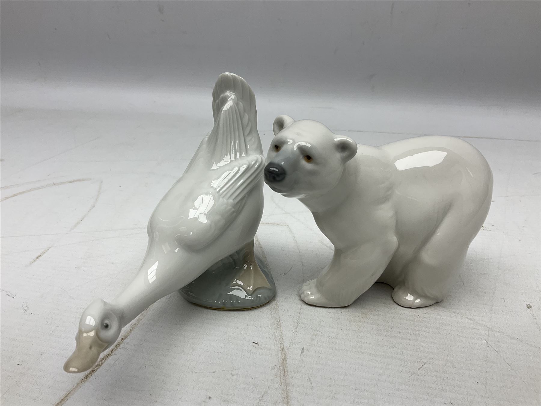 Seven Lladro figures, comprising Playful Puppy no 9135, Platero and Marcelino/Boy Hugging Donkey no 1181, Mini Seal Family no 5318, Attentive Polar Bear no 1207, Seated Polar Bear no1209, Eskimo Boy with Pet no 5238 and Girl with Geese no 1035, together with Nao goose