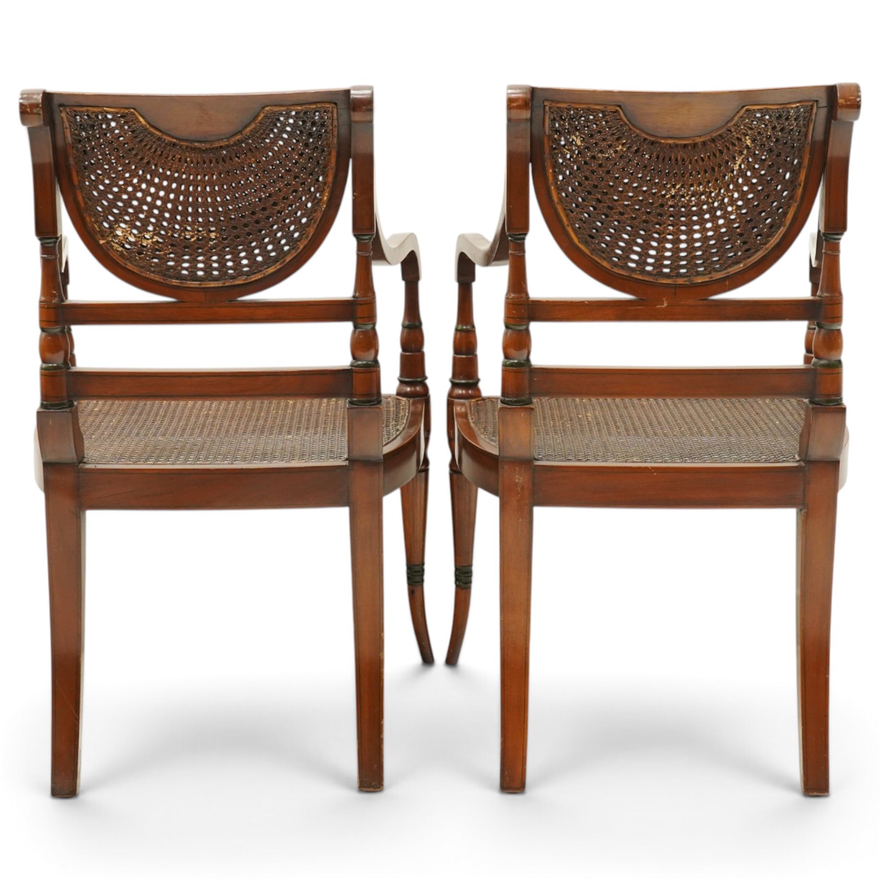 Pair of Sheraton Revival painted mahogany open armchairs, scrolled cresting rail with floral painted decoration over a double-caned back and rose-branch painted back bar, cane seat over C-scroll-painted seat rail, on splayed tapering supports, with all-over painted ebony faux stringing