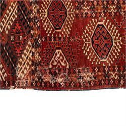Persian Bokhara crimson ground rug, the field decorated with five rows of repeating Gul motifs with interspersed geometric design, enclosed by a guard band of further geometric-style Gul designs comprised of hook motifs