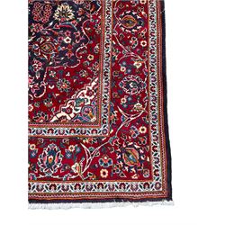 Persian indigo ground rug, the central crimson pole lozenge medallion surrounded by interlacing floral patterns, the main border with repeating plant motifs connected by scrolling branches