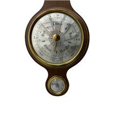A contemporary German Aneroid barometer in a mahogany effect case with a broken pediment and finial, silvered register measuring barometric pressure in inches and millibars with weather predictions, indicator hand and adjustable recording hand within a gilt spun bezel and flat glass, circular hygrometer and mercury thermometer recording the temperature in degrees Fahrenheit and Celsius