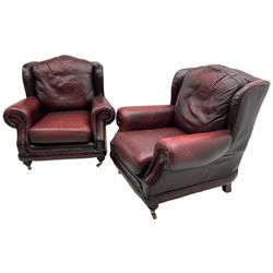 Thomas Lloyd - three-piece lounge suite, comprising of traditional shape two seat sofa (W190cm H80cm) and a pair of wingback armchairs (W100cm H91cm), each with rolled arms over turned supports with brass castors, upholstered in oxblood red leather