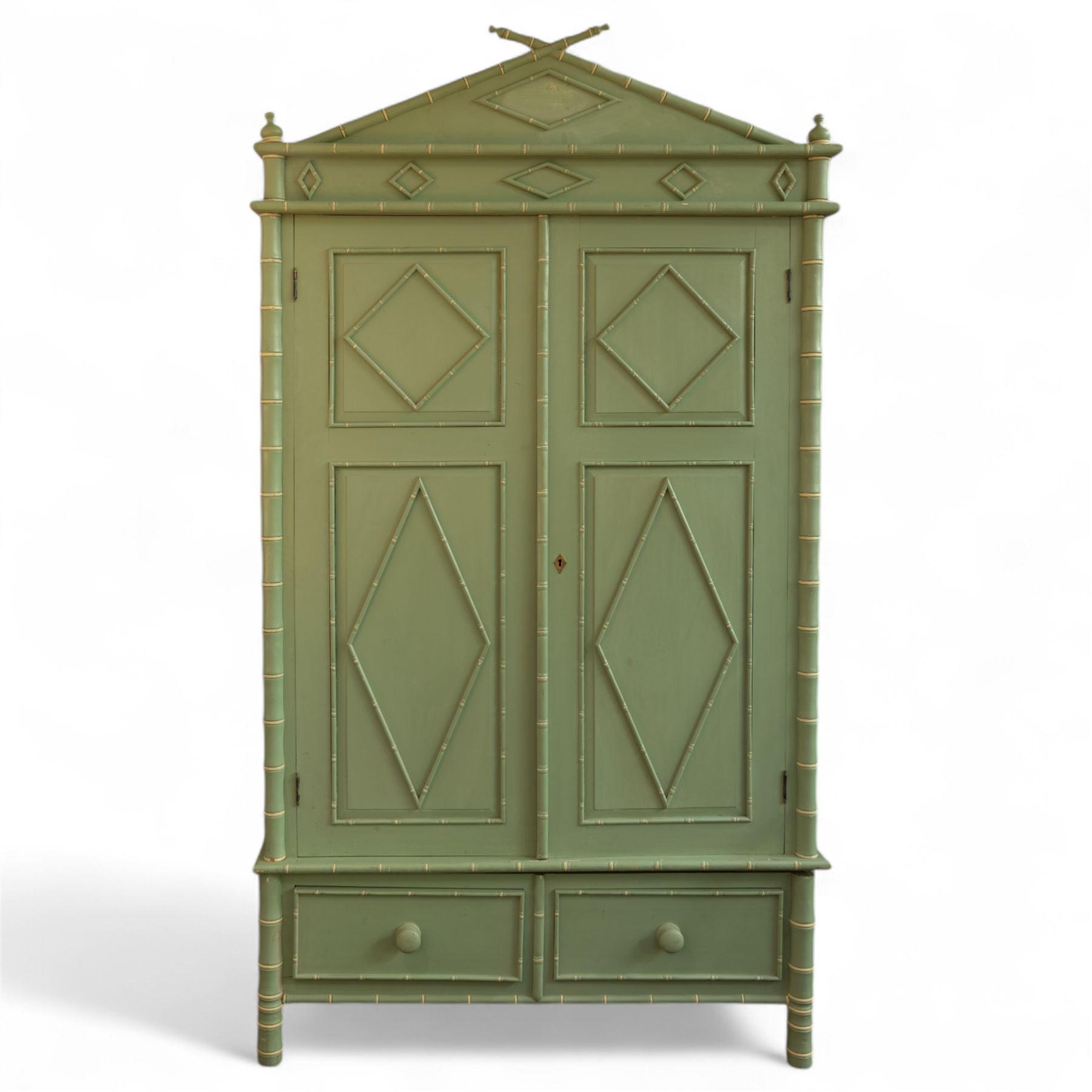 Regency design chinoiserie painted pine armoire, finished in sage green with carved simulated bamboo mouldings, projecting pediment with central lozenge panel, frieze decorated with small lozenges  surmounted by crossed finials, twin doors with diamond-shaped mouldings, interior with hanging cupboard, framed by full-length faux bamboo pilasters, above lower section with two short drawers on post feet 