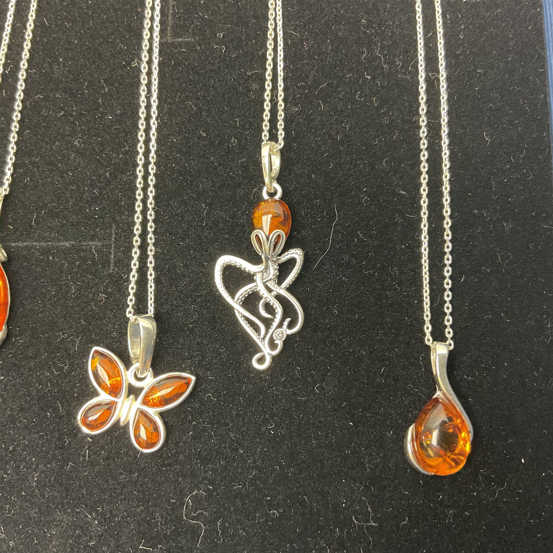 Seven silver Baltic amber pendant necklaces, including octopus and butterfly designs, all stamped 925 