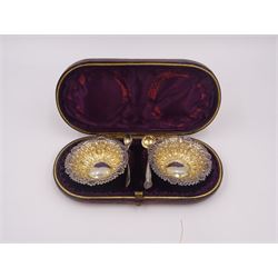 Pair of Victorian silver open salts, of part fluted navette form, with engraved foliate decoration, upon oval stepped foot, hallmarked W H Lyde, Birmingham 1896, H3.5cm, together with a pair of silver salt spoons, with leaf shaped bowls and ball finials, hallmarked Joseph Gloster, Birmingham 1897, together with a pair of Victorian silver open salts, of circular form, with shaped rim and embossed scroll and lattice decoration to the gilded bowl, together with pair of matching silver salt spoons, hallmarked Albert Sydenham, Birmingham 1899, both sets within tooled leather, velvet and silk lined fitted cases