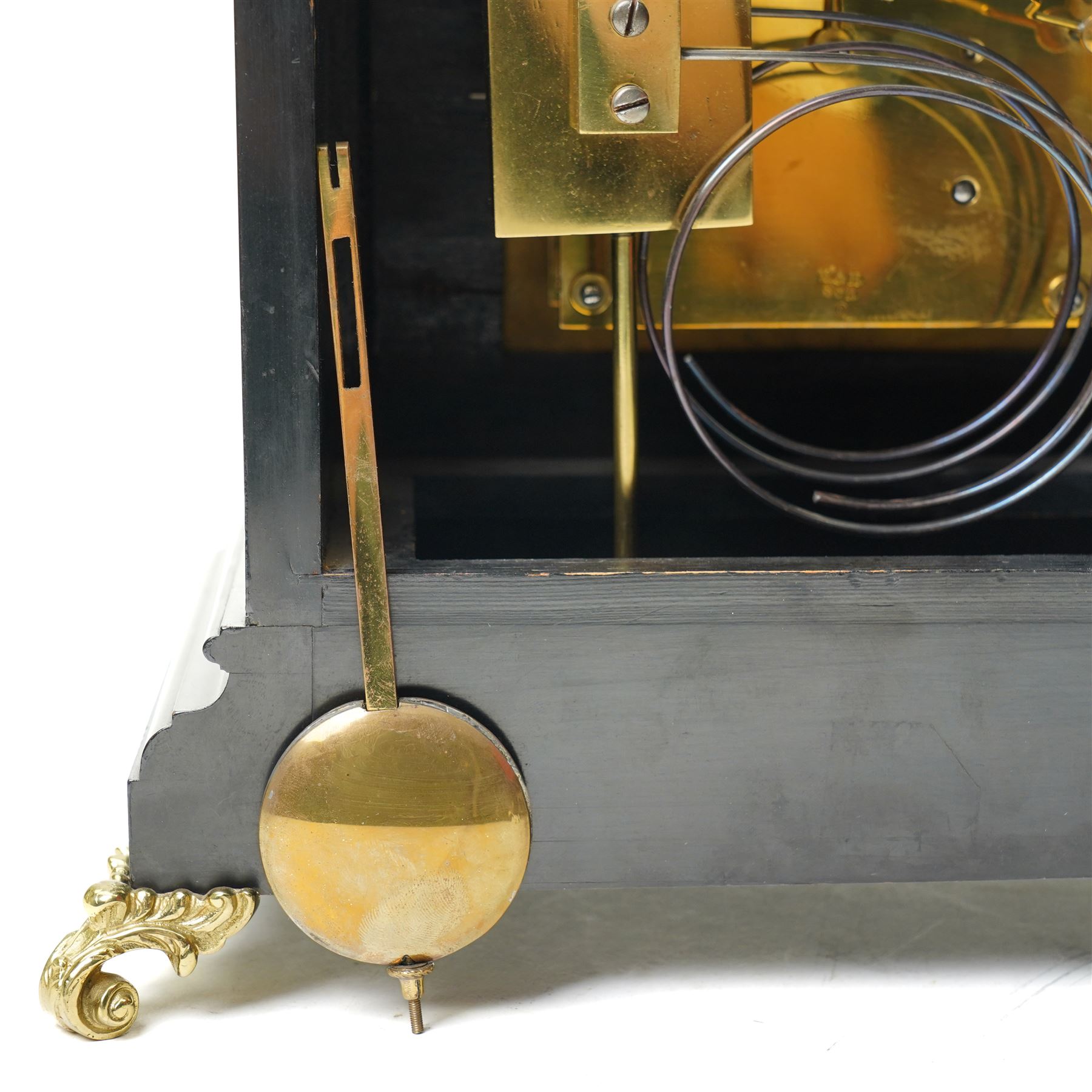 Winterhalder & Hoffmeier-8-day early 20th century mantel clock with an ebonised finish, break arch pediment and two matching brass finials, conforming glazed door with a cast brass bezel flanked by reeded quarter pilasters, on a moulded plinth with scroll feet, brass dial with cast spandrels and strike/silent and pendulum regulation dials to the arch, matted dial centre with a silvered chapter, Roman numerals  and gothic steel hands, dial pinned to a quarter striking movement sounding the quarters on two gongs and hours on one. With Pendulum.
