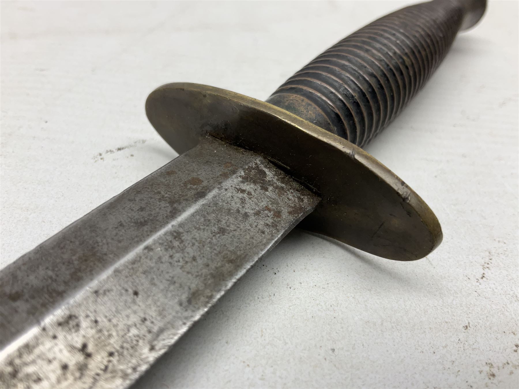 Fairburn and Sykes Commando fighting knife, 3rd pattern with 17cm double edged blade and copperised grip; no markings; in cut-down plain leather sheath L31.5cm