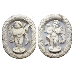  Pair of large early 20th century mahogany oval plaques carved and white painted in Wedgwood Jasper style as winged cherubs with horn & lute on a blue ground in wreath surround, H91cm, W70cm (2)   