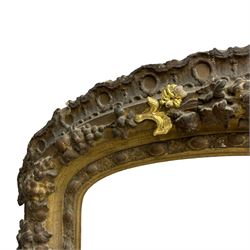 19th century giltwood and gesso moulded picture or mirror frame, the arched cresting rail mounted by central cartouche decorated with foliate scrolls and fruit, the outer frame decorated with scalloped edge and shell mouldings, trailing foliage with flower head and fruit to the central band, egg and dart moulded inner slip