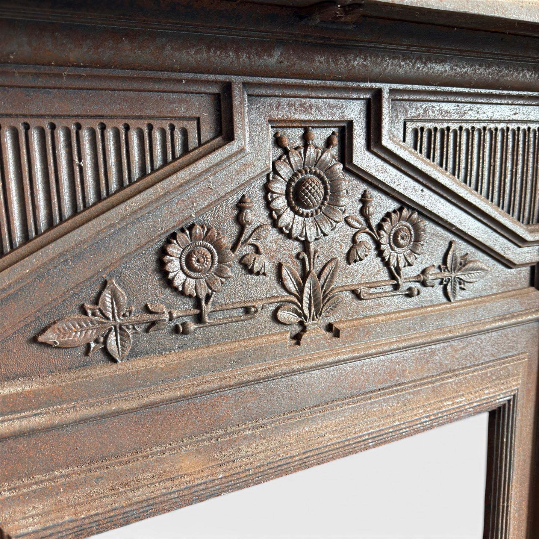 Late Victorian cast ion bedroom fireplace, decorated with floral poppy motifs and flluting