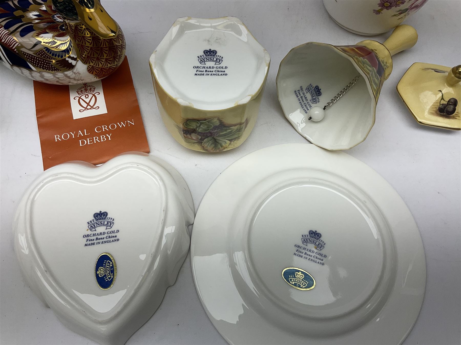 Royal Crown Derby paperweight in the form of a mallard duck, with gold stopper, together with Aynsley Orchard Gold lidded jar, bell, dish and plate, and Derby Posies pattern jar and cover, four with boxes