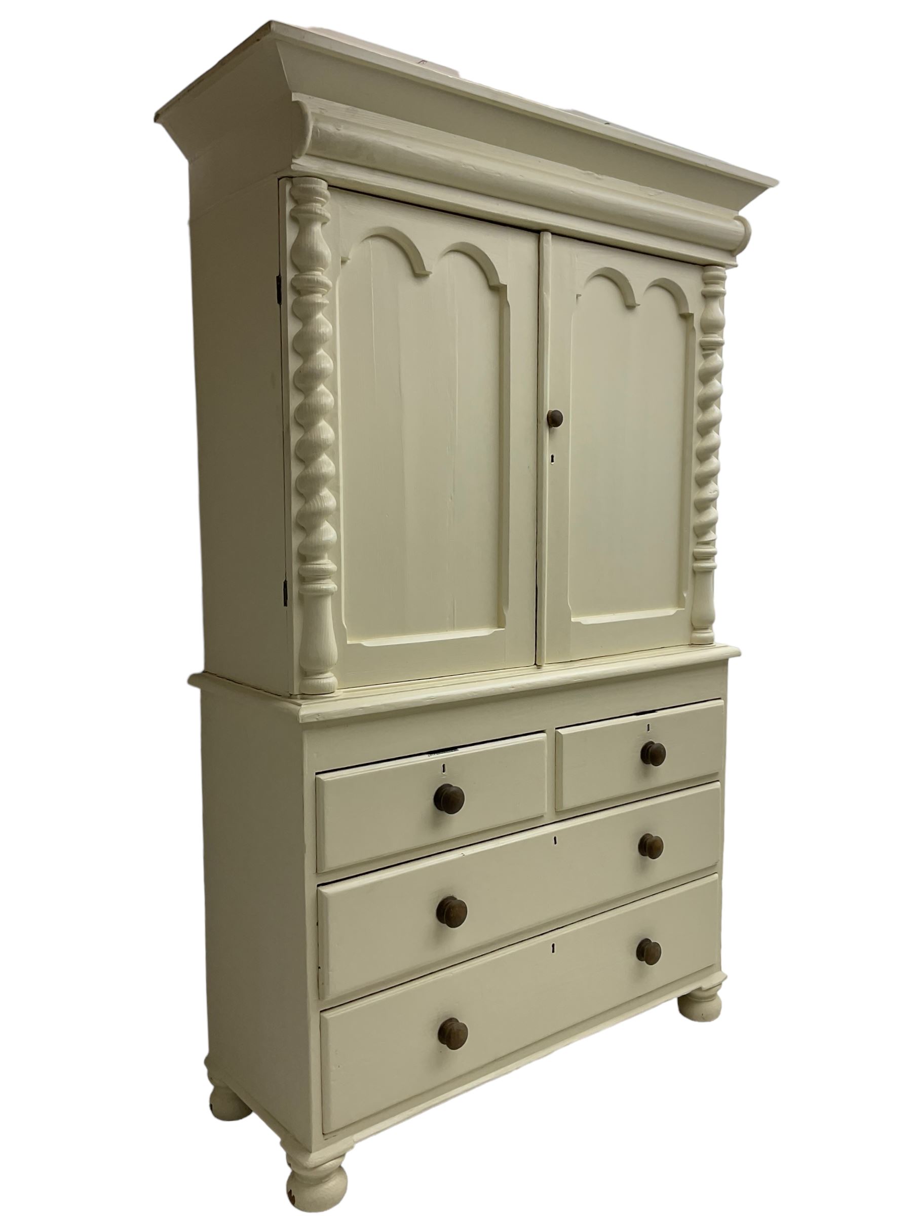 Victorian cream painted pine cupboard-on-chest or housekeeper's cupboard, projecting cornice over two double-arch panelled cupboard doors enclosing two shelves, flanked by spiral turned uprights, base fitted with two short over two long drawers, on bun feet