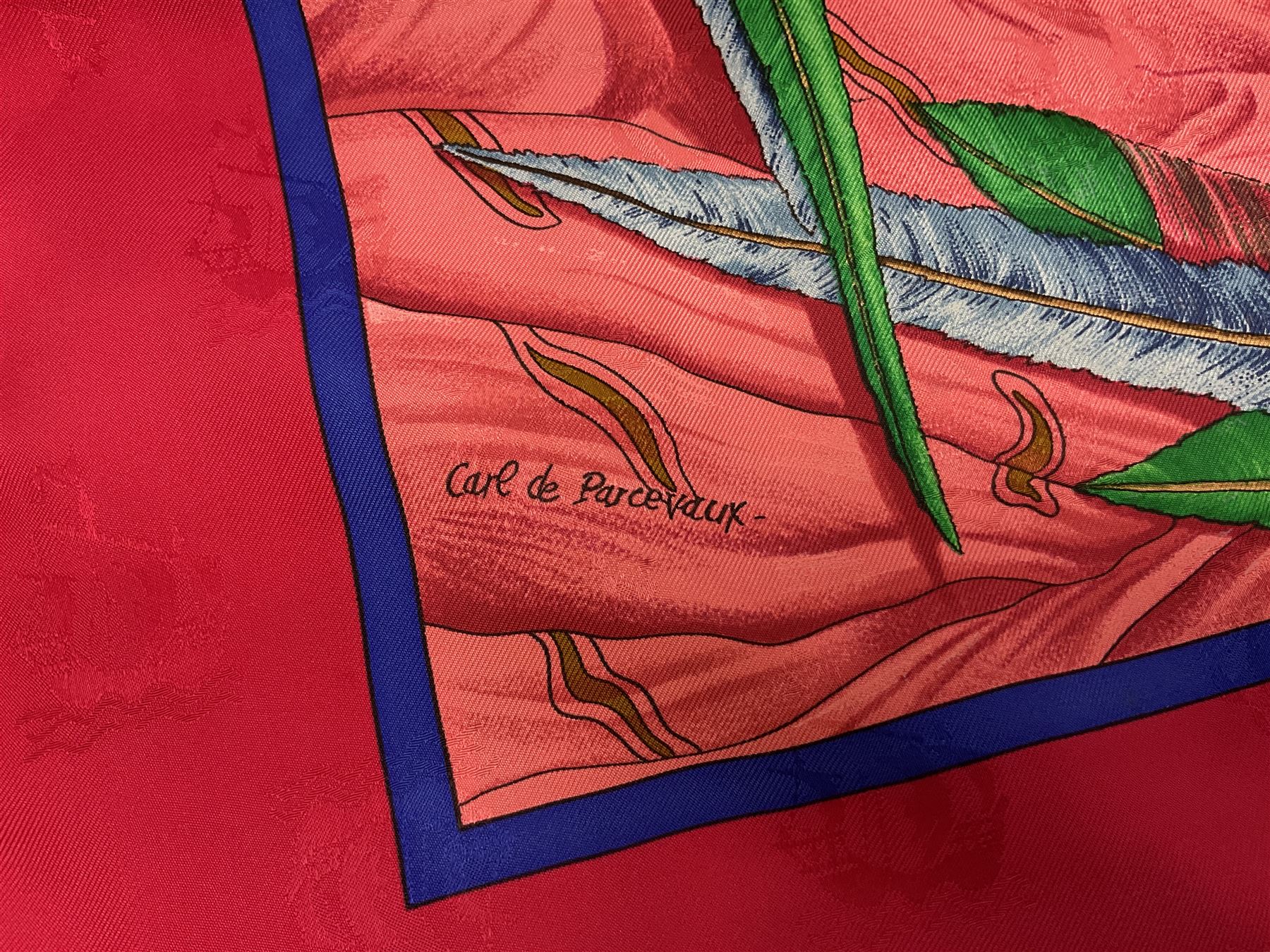 Hermès 'Christophe Colomb Découvre l'Amérique' jacquard silk scarf, designed by Carl de Parcevaux in 1992, limited edition for the bi-centenary of the discovery of America, printed with a central image of Christopher Columbus' ship at sea, surrounded with colourful stylised feathers, birds, flags, globes, shells and flowers, contained within vibrant red border, with rolled hand stitched edges and Hermes material label, 87cm square