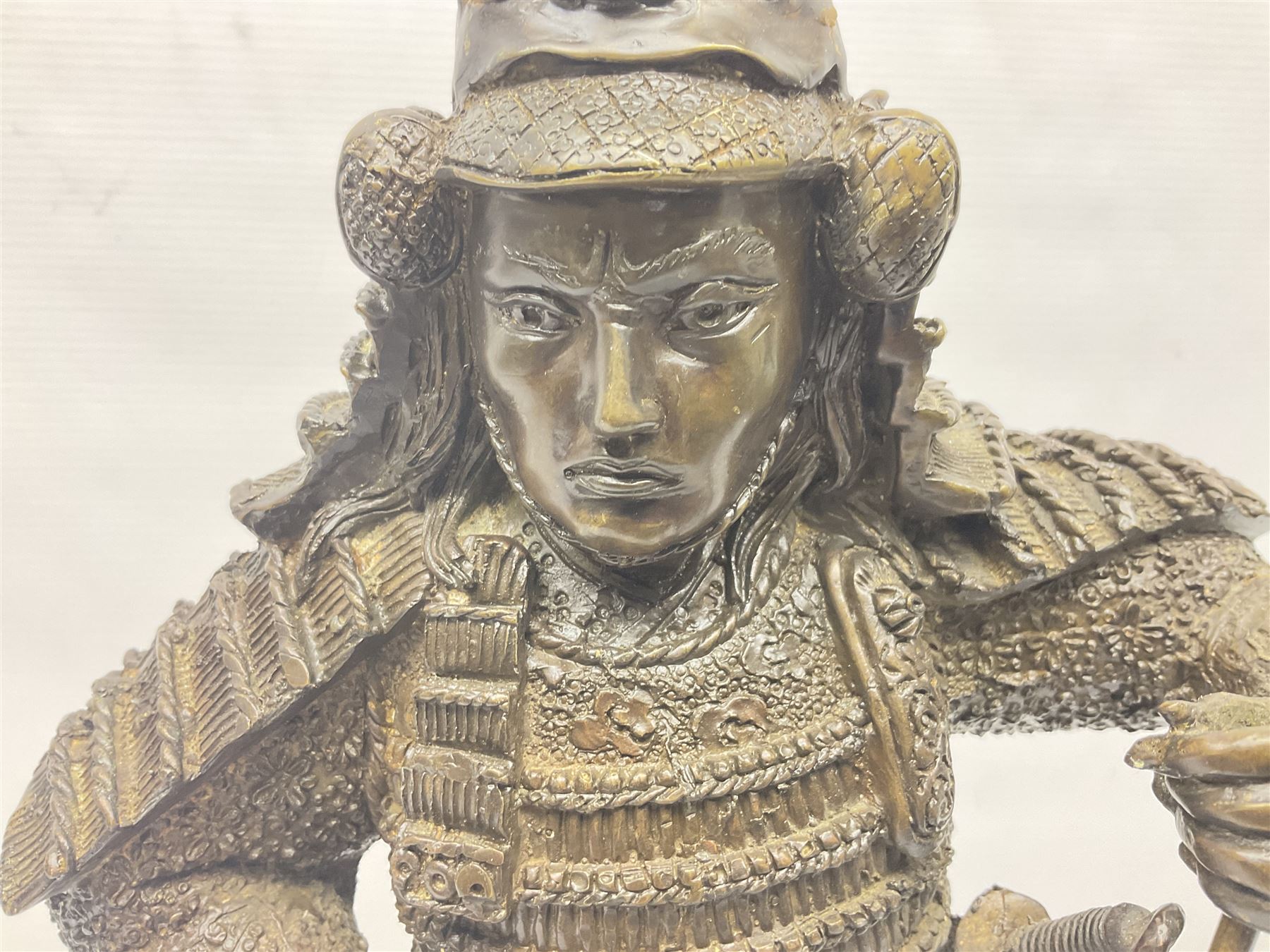 Bronze figure of a samurai standing wearing armour and holding a naginata, upon a rocky base, H48cm