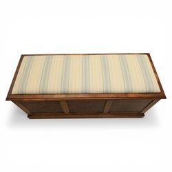 Traditional design figured elm blanket chest, with padded striped upholstered seat, over a hinged top with panelled sections below raised on a plinth base