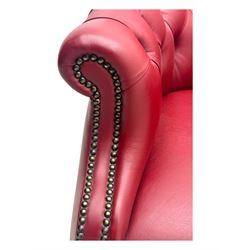 Kingsgate - contemporary 'Devon' bucket armchair, upholstered in red leather with buttoned backrest, rolled arms and brass stud detailing, raised on four dark wood supports with vertical carving