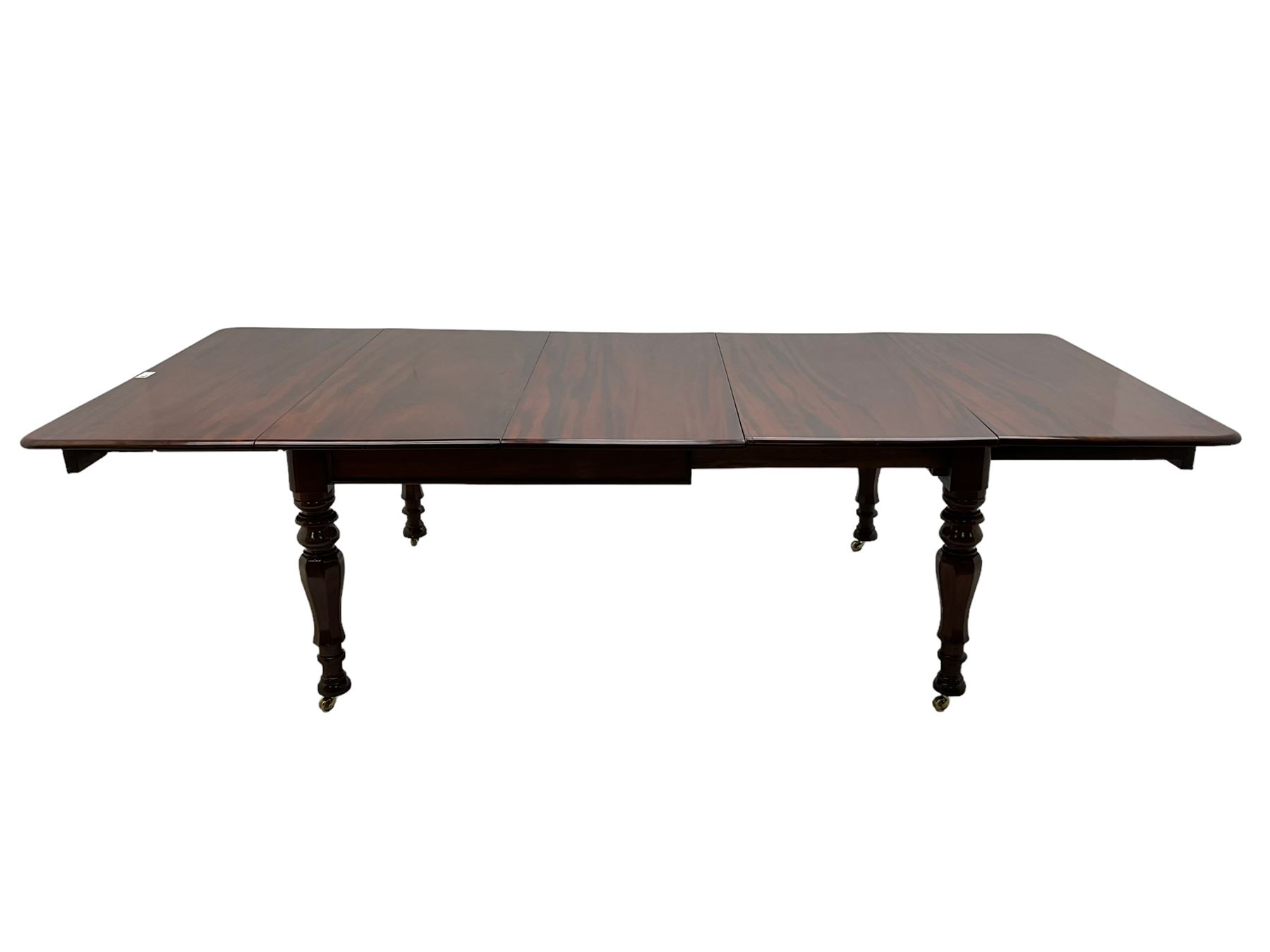 19th century mahogany extending dining table with three additional leaves, rectangular top with rounded corners, pull-out action, on turned and faceted supports with brass castors
