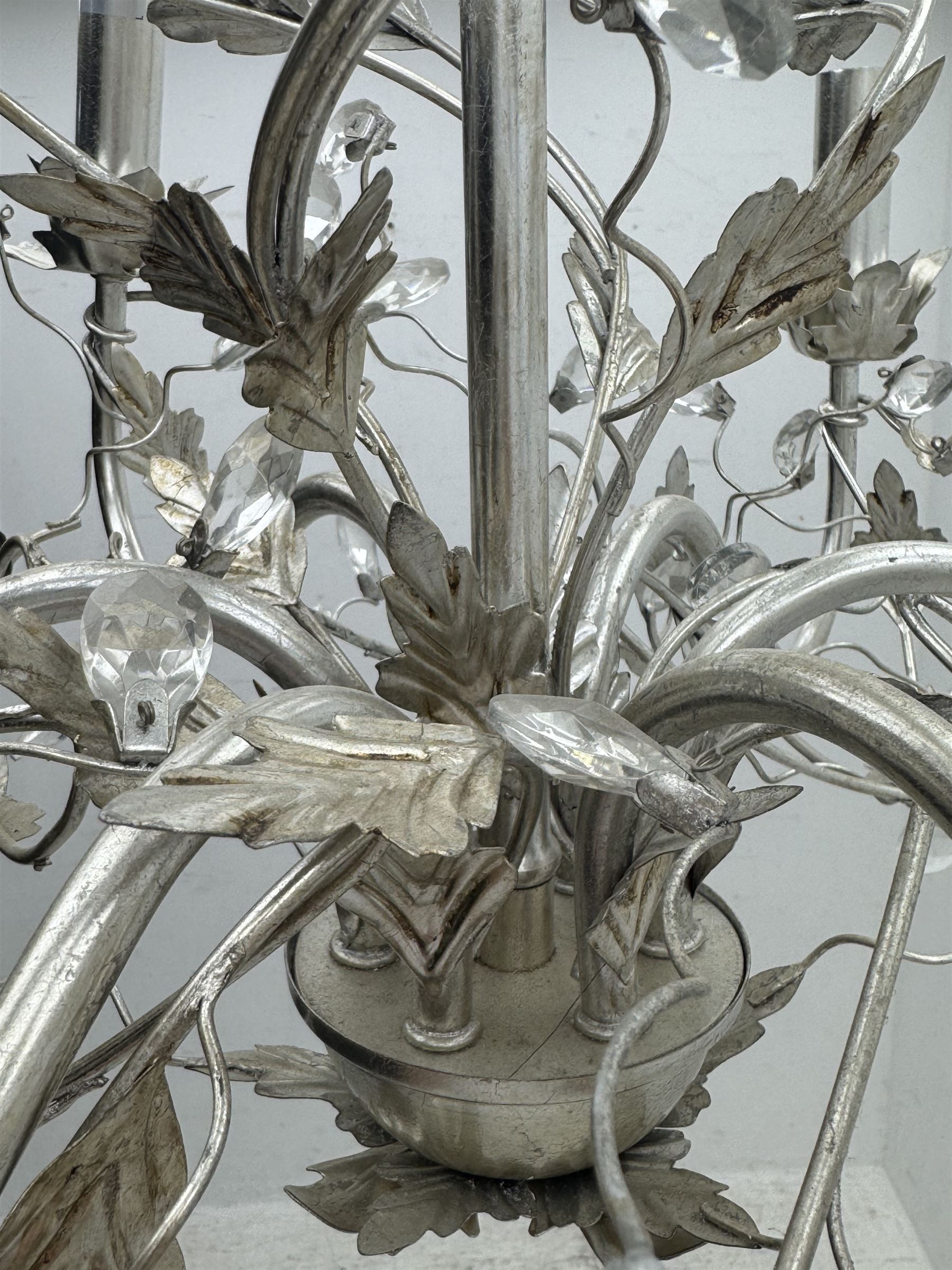 India Jane - silver finish metal chandelier, modelled with scrolling vines and leaves, embellished with faceted glass drops, fitted with six candle sconces, and wired for electricity