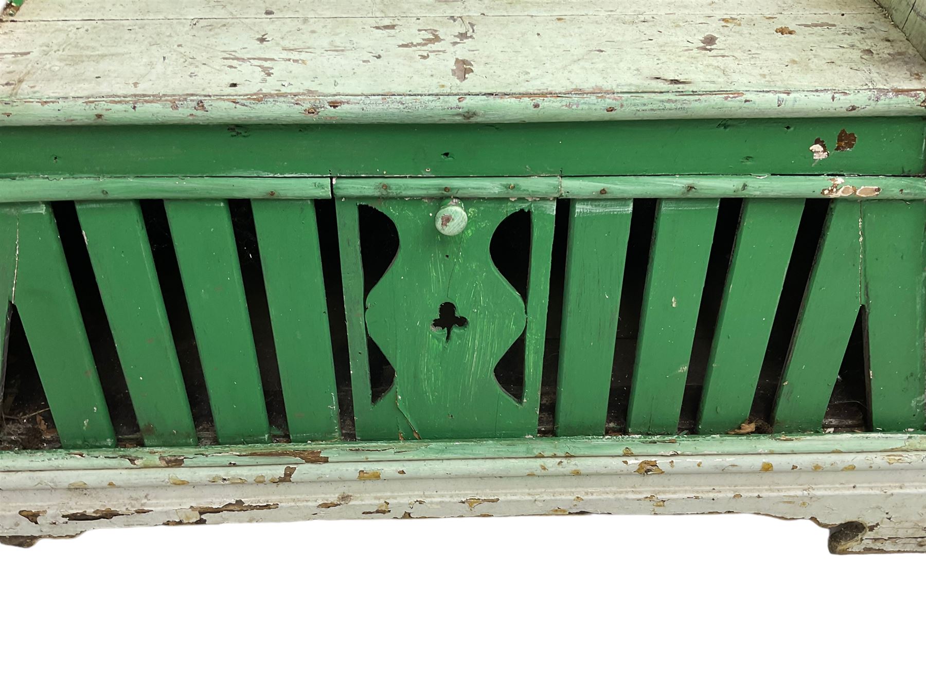 19th century painted pine hen coop settle, overhanging arched canape with dentil moulding and shaped edge, the panelled seat over a triangular platform base with removable hen-coop door, in green and white finish