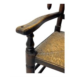 Early 19th century ash armchair, the back with winged spindles extending from a shaped top rail, above a splat of two rows of vertical spindles, with curved arms and a rush seat, raised on turned supports united by double stretchers terminating in castors