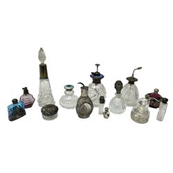 Silver collared and lidded glass perfume bottles and atomisers, to include a Hong Kong bottle covered with oriental sterling silver design with three concave oval windows, cylindrical glass scent bottle with foliate silver screw thread cap stamped Birmingham 1911 and six other silver capped examples, along with seven white metal mounted glass scent bottles including coloured and faceted examples (15)