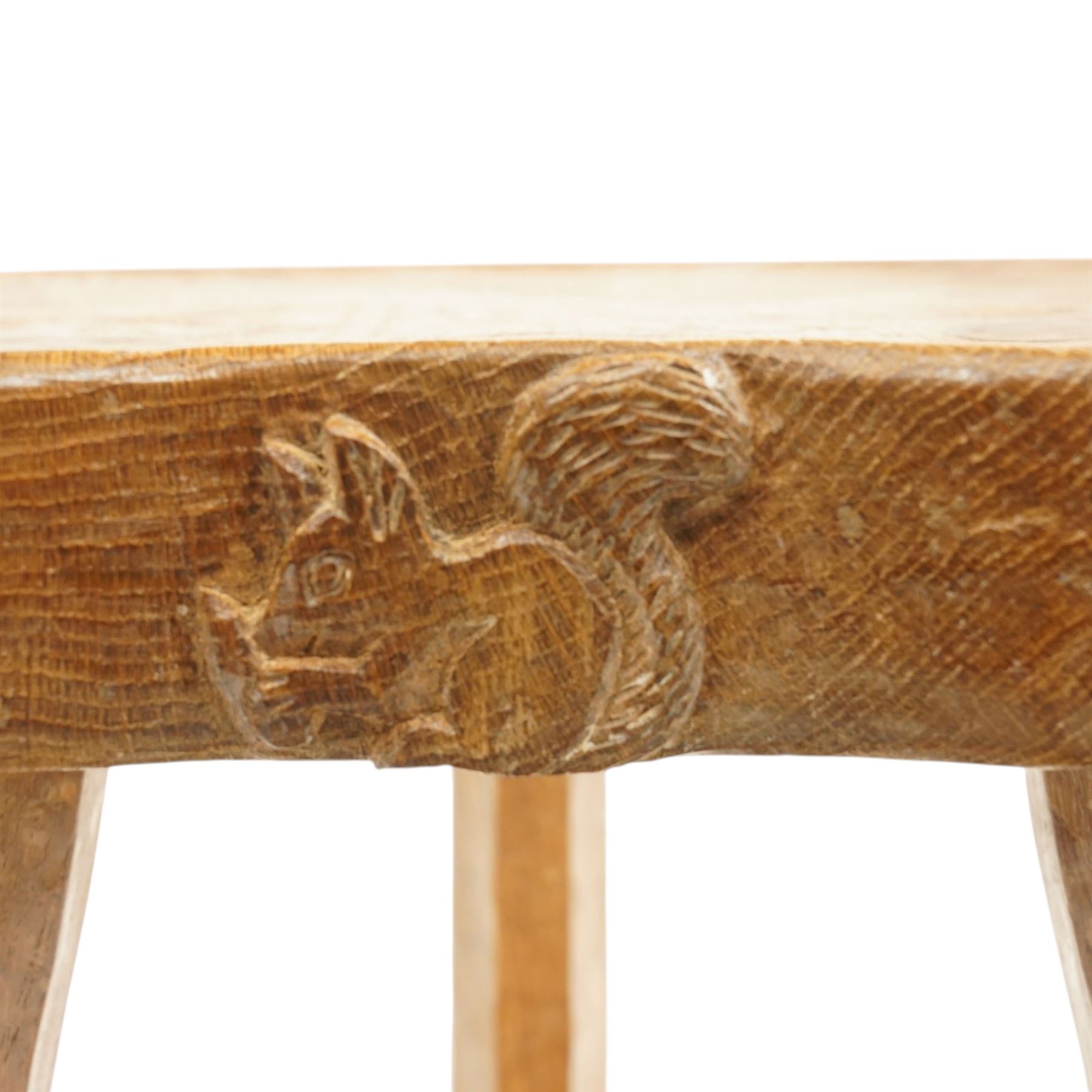 Squirrelman - rustic oak milking stool, adzed shaped top with exposed peg construction, on three tapering supports, with large carved squirrel signature, by Wilf Hutchinson, Husthwaite