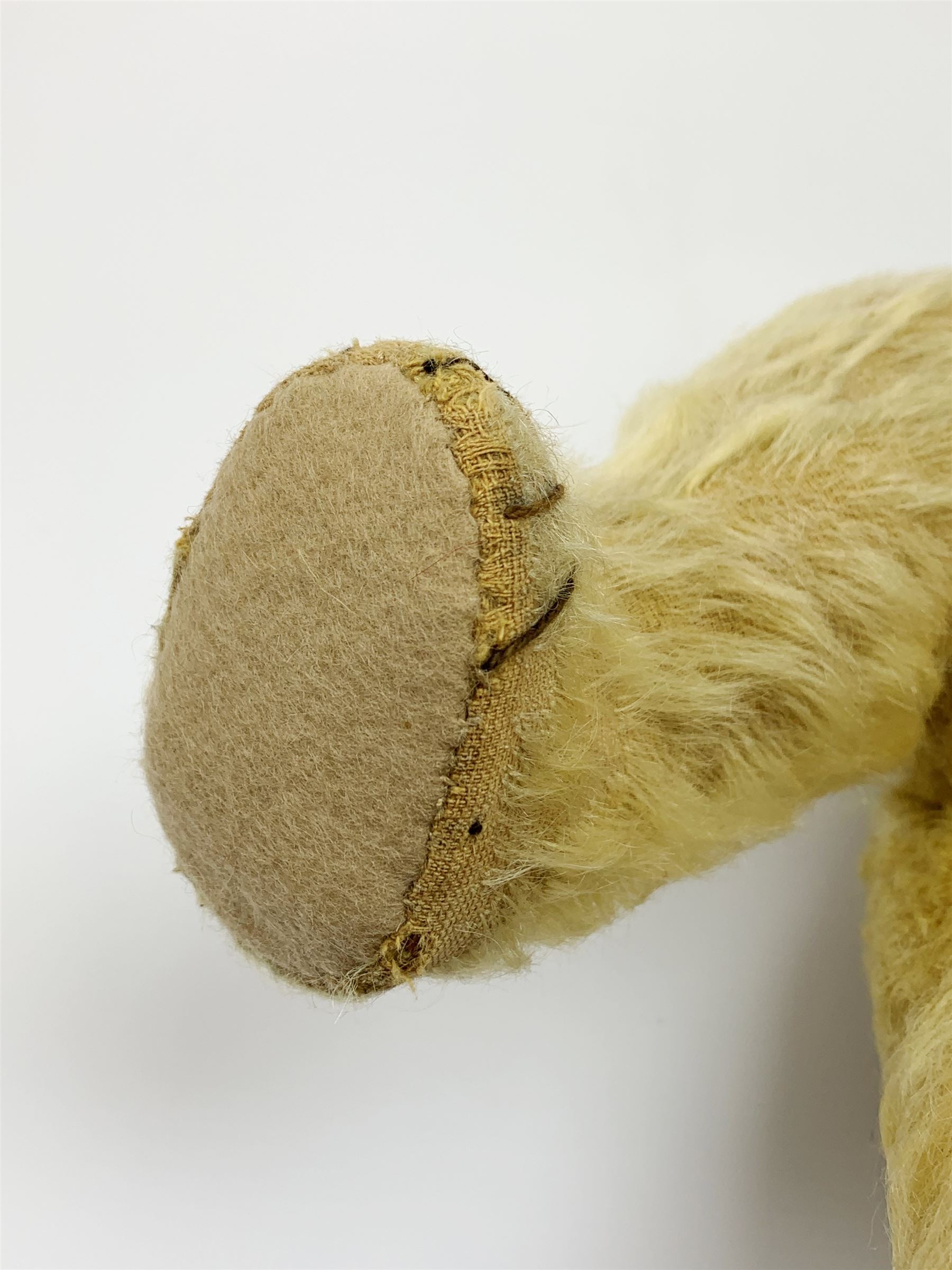 1930s teddy bear, possibly Farnell, with wood wool filled blond mohair body, the revolving head with original clear glass eyes, shaved muzzle with vertically stitched nose and mouth and jointed limbs with five-stitch claws H18.5