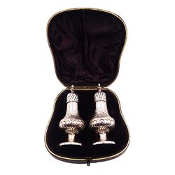 Pair of Victorian silver pepper shakers, each of baluster form with part fluted body, embossed with florals and scrolls, the fluted pierced covers with urn finials, upon a circular foot, hallmarked Hayes Brothers, Birmingham 1893, H10cm, contained within tooled leather silk and velvet lined fitted case 