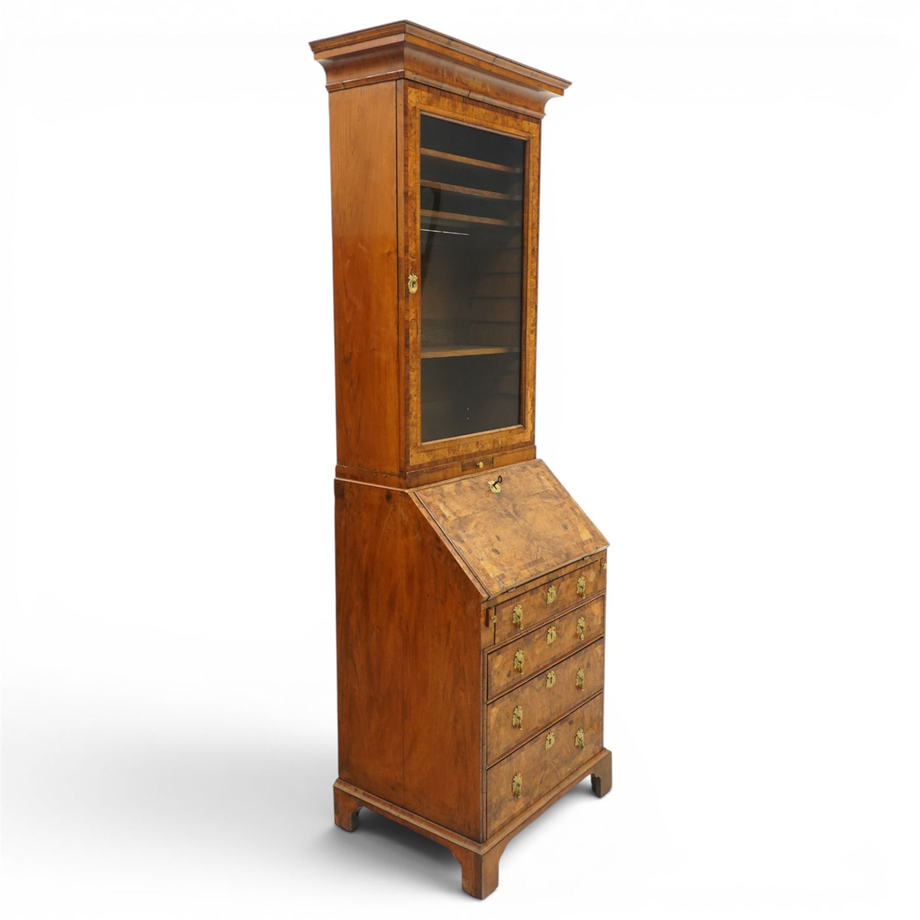Quality George I figured and burr walnut bureau-cabinet of unusually small proportions, the projecting cavetto cornice over a glazed and banded door enclosing four adjustable shelves, with a candle slide below, the book-matched and banded veneer fall-front enclosing a fitted interior with pigeonholes, correspondence drawers and original trinket boxes and inkwells, over two pull-out stays and four graduating long drawers with banded facias and pressed brass escutcheons and pull handles, lower moulded edge on bracket feet
Provenance: purchased Sotherby's 1977