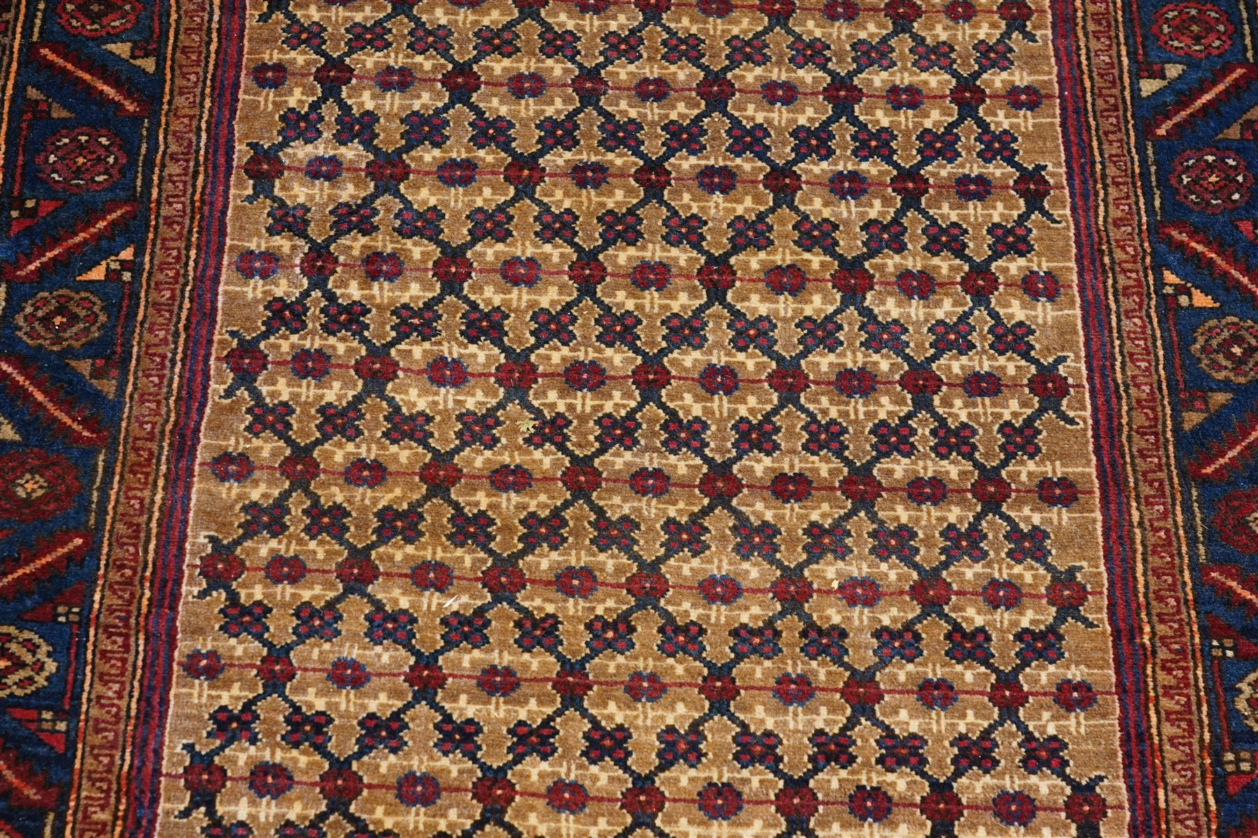 North East Persian Kurdie hand-knotted runner, camel ground with an all-over lattice of rosette motifs linked by angular vines, terminating in a stepped lozenge panel, with a madder red field, spandrels with geometric and zoomorphic devices, indigo main border of angular vines and repeating rosettes, flanked by narrow guard stripes, cotton fringe ends  