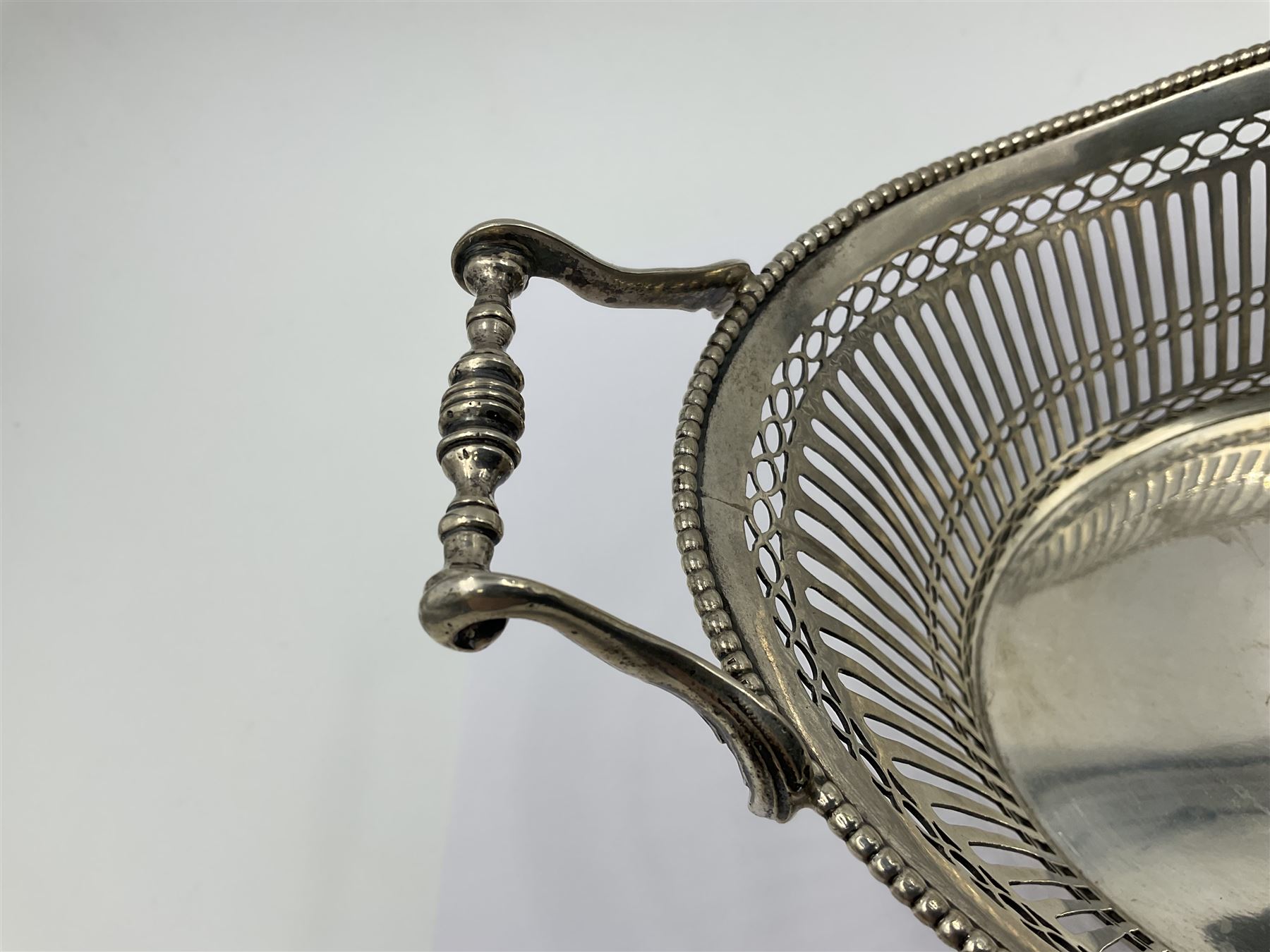 Early 20th century Dutch silver basket, of oval form with pierced sides, beaded rim, and twin handles, marked with Lion Passant for 2nd standard purity and date letter for 1910, other marks worn and indistinct, including handles H8.5cm L25.5cm