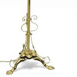 20th century brass standard lamp, urn form reservoir top with hinged cover, on a slender column with knopped detail, the stem fitted with scrolling supports, raised on a triform base with shaped cabriole supports terminating in pad feet