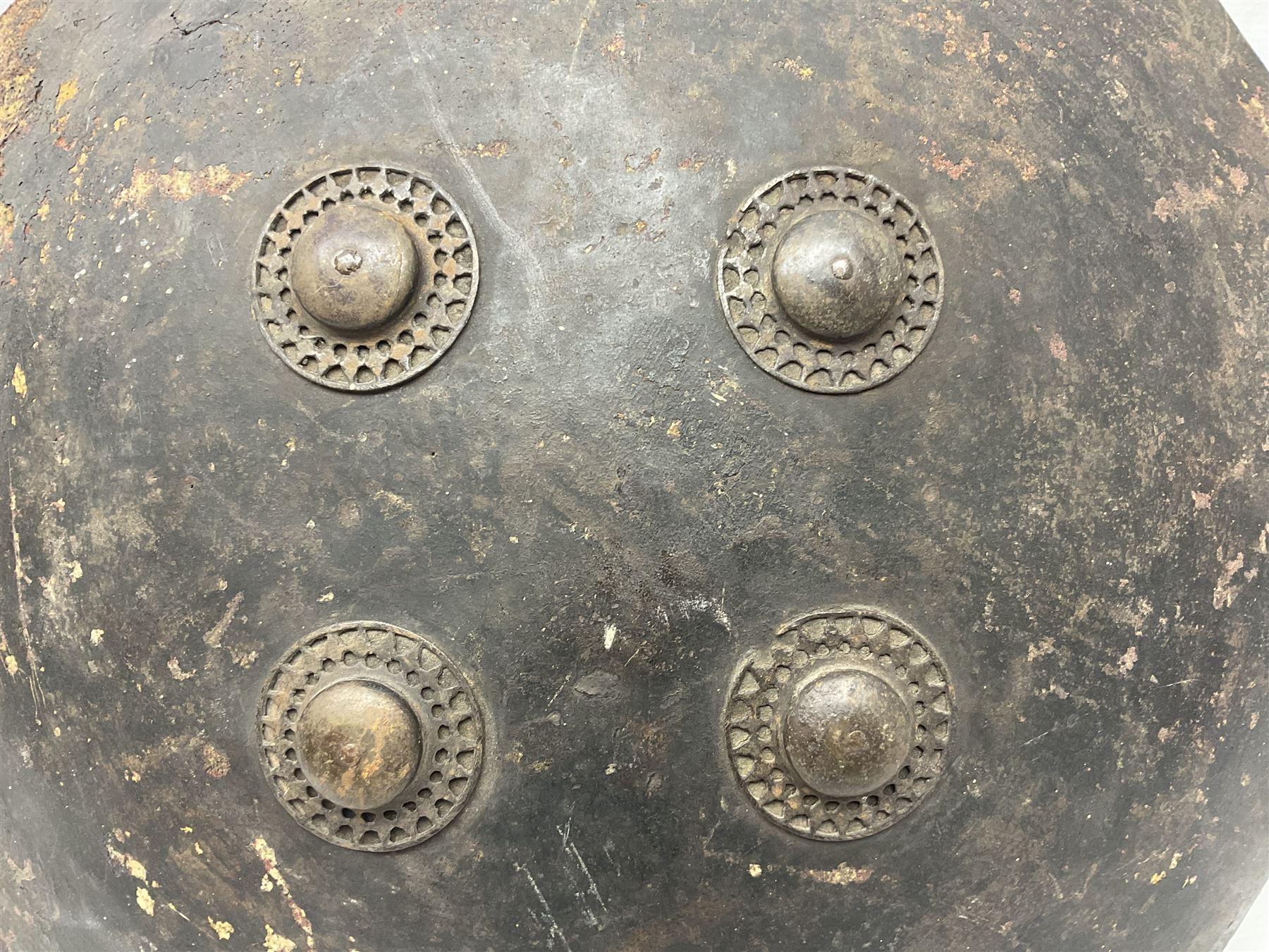 Indian black lacquered hide shield/dhal, of circular convex form fitted at its centre with four pierced iron bosses, each of hemispherical form with wide brims, the bosses corresponding on the inside with four iron rings for enarmes D53.5cm