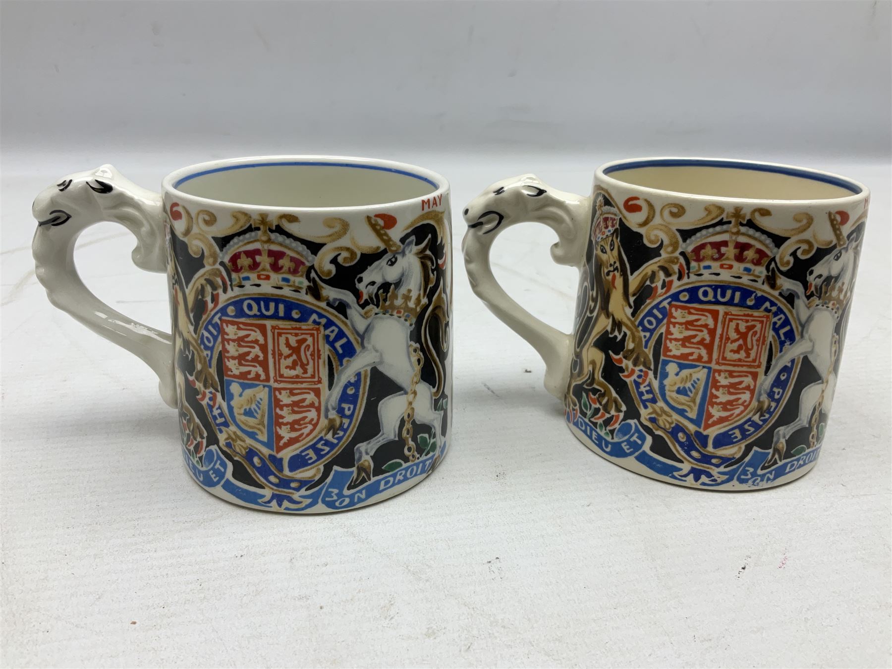 Two Dame Laura Knight coronation mugs for King George VI and Queen Elizabeth, comprising a Burleigh Ware example and a J&G Meakin example, each with a lion moulded handle and printed marks beneath, H8cm
