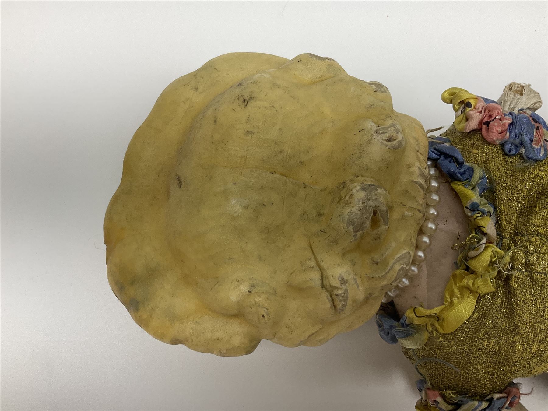 Victorian large wax over composition Pumpkin head doll, with inset dark glass eyes, moulded blonde hair in curls, stuffed body with carved and painted wooden limbs, grey painted boots, floral satin dress with netting underclothes H61cm