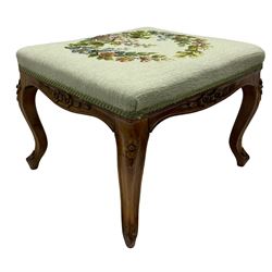 19th century French walnut dressing stool, rectangular seat upholstered in a floral needlework tapestry top, shaped apron with applied carved flower heads, on cabriole supports with acanthus carved feet