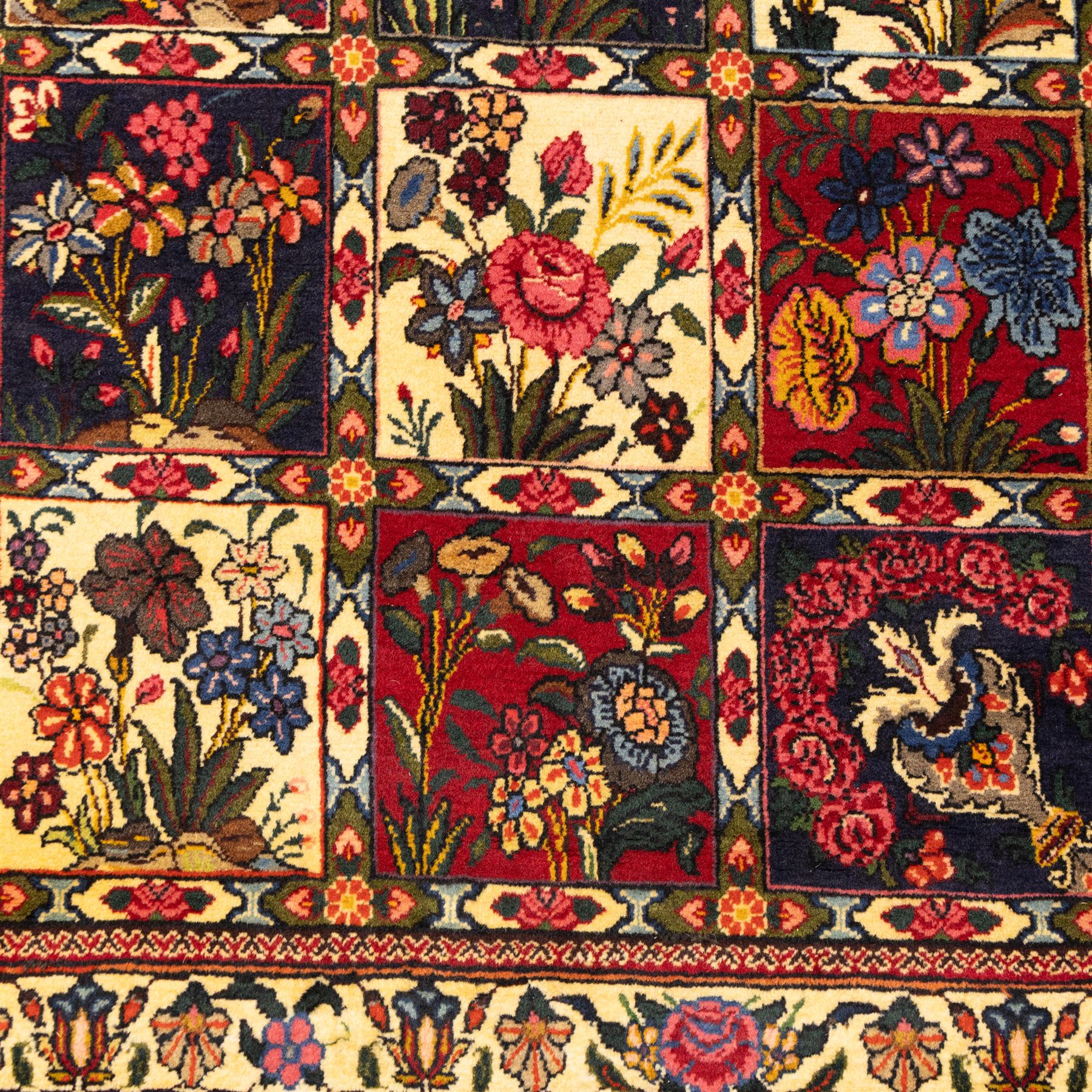 Central Persian Bakhtiar hand-knotted runner, field arranged with a garden panel  design of floral sprays and foliage within a flowerhead and vine border, in tones of crimson, ivory, and indigo with cotton fringe ends 
