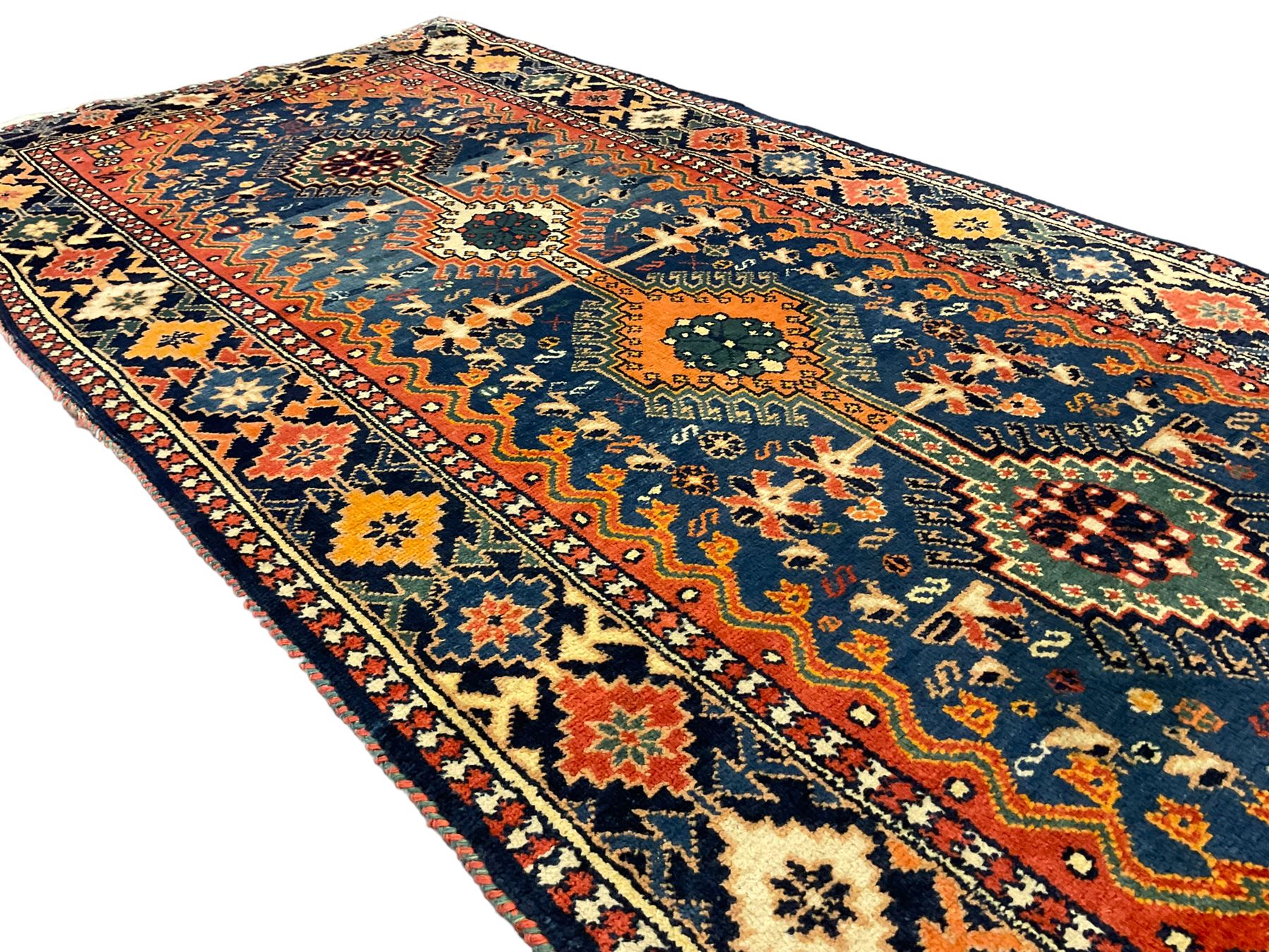 Persian blue ground rug, field decorated with four pole medallions with surrounding repeating bird motifs, coral spandrels with flowerheads, guarded border decorated with repeating geometric lozenges