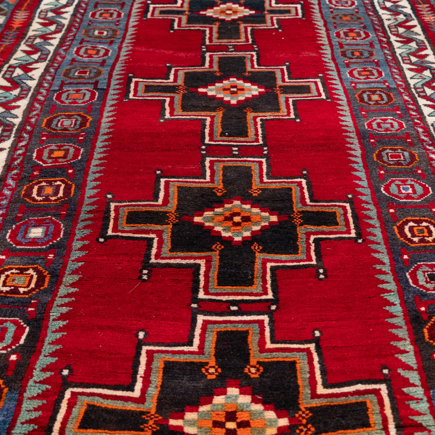 South-west Persian Lori rug, the red field centred by four linked stepped cruciform medallions with polychrome diamond centres, enclosed by a blue ground octagonal motif border, ivory angular meander band and red geometric outer border