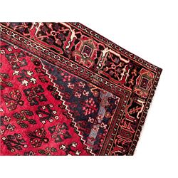 Persian Joshaghan crimson ground rug, stepped lozenge medallion surrounded by repeating foliate lozenge motifs, the border decorated with stylised plant motifs, within geometric guard stripes 